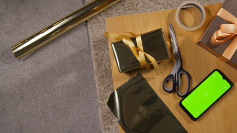 Overhead-Shot-Of-Gift-Or-Present-Being-Wrapped-On-Table-At-Home-With-Green-Screen-Mobile-Phone